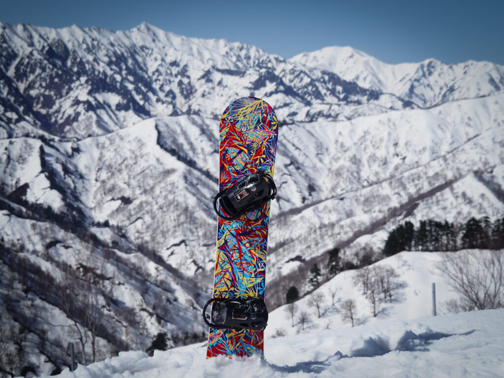 奥只見丸山スキー場の雪山を背に、雪面に刺さるハンドペイントのスノーボードアート作品